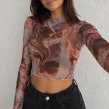 Top de microtul de manga larga con estampado marmolado en tonos marrones y rojizos. Presenta cuello redondo y terminaciones con borde ondulado.
