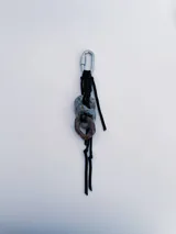 Charm para bolso o accesorios con mosquetón metálico, tejido de macramé en cordón negro y dijes de cerámica esmaltada en tonos violeta y celeste.
