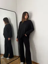 Conjunto de dos piezas en color negro, compuesto por un sweater de corte holgado con cuello redondo y mangas largas, y un pantalón de tiro alto y pierna ancha. Ambas prendas están confeccionadas en tejido de angorina suave.