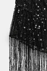 Top negro de lentejuelas con cuello halter, escote fluido, espalda descubierta y flecos en el bajo.