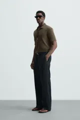 Polo negro de manga corta con cuello solapa y abertura frontal. Presenta un tejido jacquard con textura geométrica sutil.