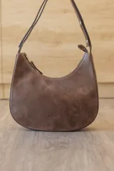 Cartera hobo de cuero color rojo con silueta curva de media luna, cierre superior y correa de hombro ajustable.