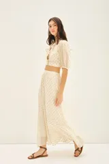 Falda larga de tiro alto, calce amplio, color crema con puntos dorados brillantes (lurex). La cintura es elástica en la parte trasera y tiene frunces.