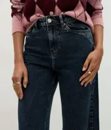 Pantalón wide leg de tiro alto en denim azul oscuro, con trabillas para cinturón, cierre de botón y cremallera, y bolsillos delanteros y traseros.