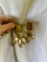 Aros colgantes dorados con forma rectangular y tres dijes en forma de hoja.