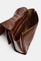 Bolso tipo mini shopper confeccionado en piel con acabado brillante. Presenta un diseño de doble compartimento con cierre de botón imantado y asa de hombro ajustable.