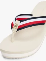 Sandalias tipo ojota con plataforma de cuña alta, color beige claro. Las tiras son de tejido trenzado con las franjas distintivas de Tommy Hilfiger (azul marino, blanco y rojo).