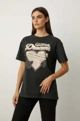 Remera de algodón color negro con cuello redondo y mangas cortas. Presenta un estampado frontal con diseño de rosas, rayos y texto, decorado con detalles de strass.