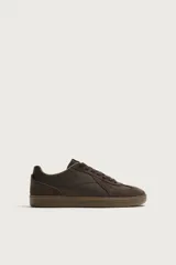 Zapatilla deportiva estilo retro en color marrón, confeccionada con una combinación de piezas de cuero sintético y gamuza, con suela de goma a tono.