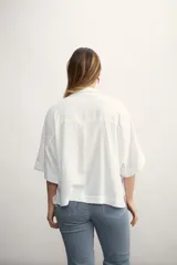 Blusa negra de corte holgado con cuello polo y cierre frontal parcial. Presenta mangas cortas amplias y un diseño minimalista.
