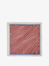 Pañuelo cuadrado confeccionado en mezcla de algodón y seda. Presenta un diseño de lunares blancos sobre fondo bordó, con un borde interior azul y un borde exterior beige.