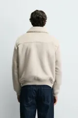 Cazadora regular fit de tejido efecto ante con interior de borreguillo a tono. Presenta cuello solapa, cierre frontal con cremallera, bolsillos de vivo en la cadera y acabados en rib en puños y bajo.