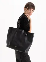 Cartera tipo shopper Jazmin Chebar modelo Honey, color negro, confeccionada en cuero vacuno suave. Cuenta con amplia capacidad, doble asa larga para el hombro y diseño grabado con abejas en bajo relieve. Incluye un tag colgante decorativo con dije metálico en forma de abeja.