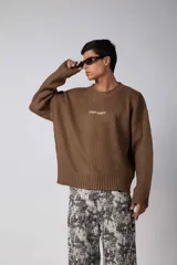 Sweater de punto acanalado con diseño de calce relajado, cuello redondo y mangas largas. Presenta una estampa gráfica pequeña en el centro del pecho y un parche con logo en el puño.