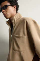 Sudadera regular fit de color beige, confeccionada en tejido con algodón, con cuello subido, cierre frontal de cremallera parcial, manga larga, bolsillo plastrón en el pecho y acabados en rib elástico.