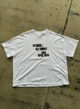 Remerón blanco de manga corta, con cuello redondo y diseño holgado. Cuenta con un estampado frontal con texto en color negro.