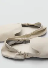 Zapato tipo flat de cuero ovino en color blanco, con diseño de punta redonda y detalle de fruncido elástico en el empeine.