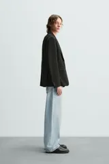 Blazer azul marino de corte recto, confeccionada en tejido con viscosa. Tiene cuello con solapas de muesca, manga larga con puño abotonado, bolsillo de vivo en el pecho y bolsillos de parche en la cadera. El bajo tiene aberturas en la espalda y el cierre es con botonadura frontal.