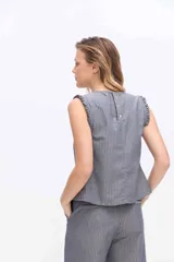 Musculosa gris a rayas verticales, con cuello redondo y detalles de volados fruncidos en la línea central delantera y en las sisas.