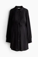 Camisa de viscosa color negro, con cuello camisero, botonadura frontal y manga larga con hombros caídos y puños abotonados. Cuenta con un cinturón fino para atar debajo del busto y diseño de bajo redondeado.