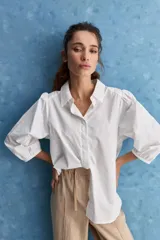 Camisa blanca de algodón, de calce relajado, con cuello camisero, frente abotonado y mangas largas abullonadas.
