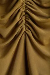 Vestido corto color ocre, sin mangas, de punto elástico con escote en V y abertura frontal con botones dorados. Corte ajustado con frunces delanteros.