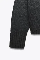 Jersey de punto con cuello redondo y manga larga, con acabados en rib ancho a tono y bajo asimétrico.