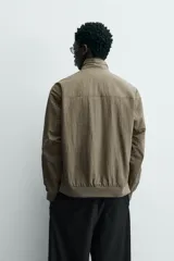 Cazadora azul marino de corte regular fit, confeccionada en tejido técnico repelente al agua. Presenta cuello subido, manga larga, bolsillos de vivo en cadera, bolsillo interior y acabados en rib en puños y bajo. Cierre frontal de cremallera oculta por solapa con botones a presión.