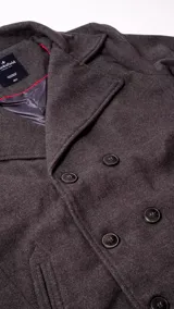 Saco de paño para hombre, estilo peacoat, de color gris oscuro. Presenta diseño de doble abotonadura, solapas clásicas y forro interior capitoneado.