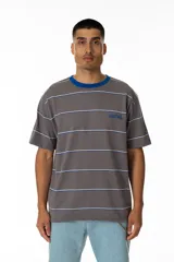 Remera gris a rayas horizontales blancas y azules, con cuello redondo azul y logo 'Vernal' bordado en azul. Corte holgado.