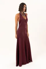 Vestido largo de color bordó, con escote halter profundo y corte a la altura de la cadera con falda amplia.