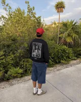 Buzo negro de cuello redondo con estampa en la espalda en formato de estampilla que muestra a una persona sosteniendo un gato.