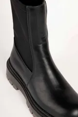 Bota baja de mujer estilo paddock, color negro, con suela track gruesa y caña de tejido elástico.