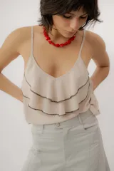 Musculosa negra con escote en V, breteles finos regulables y doble volado frontal con pespuntes.