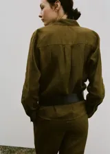 Camisa de lino color verde militar, de corte recto con cuello camisero, manga larga con puños abotonados, bolsillo de parche en el pecho y cierre frontal de botones.
