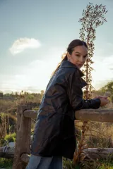 Chaqueta de cuero ovino italiano color negro, con cuello clásico, cierre frontal con botones a presión, bolsillos laterales con solapa y costuras en contraste color naranja.