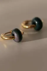 Par de aros tipo argolla dorados de acero quirúrgico, con una piedra natural de color gris translúcido colgando de cada uno.