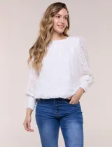 Blusa blanca de organza con textura devoré floral, silueta semiholgada y forro interno. Tiene escote bote, mangas largas abullonadas con transparencias, puños anchos con botones y ruedo elastizado.