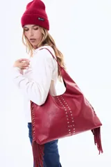 Cartera tipo hobo de cuero sintético color rojo, con detalle de tachas metálicas plateadas en el frente y flecos laterales. Cuenta con un compartimento principal amplio y correa integrada para llevar al hombro.