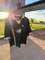 Polo de manga corta con cuello tipo polo y escote en V, corte boxy fit. Presenta un patrón texturizado en relieve y un logo ovalado con la inscripción "with love" en el pecho.