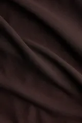 Top de punto color marrón con leve brillo, sin mangas, con detalle metálico martillado en un hombro y costuras fruncidas que generan un efecto drapeado.