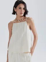 Blusa sin mangas color beige claro, con escote cuadrado y tirantes finos. La tela presenta una textura acanalada vertical.
