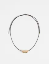 Collar de cordón negro con dije metálico de forma curva y acabado brillante.