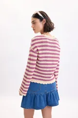 Sweater de tejido de punto fantasía a rayas horizontales en color crudo y fucsia, de manga larga y cuello redondo.