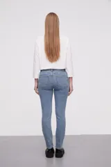 Pantalon jean de corte skinny y tiro alto, con diseño clásico de cinco bolsillos y cierre frontal con botón y cremallera.