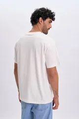 Remera oversize de manga corta en color blanco, con cuello redondo y un pequeño parche cuadrado con diseño de sol en el pecho.
