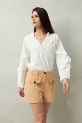 Short de algodón de tiro alto, color beige, con bolsillos delanteros tipo parche con solapa y botones a la vista.
