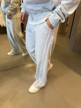 Pantalón deportivo de corte baggy y ajuste oversize, confeccionado en tejido de algodón gris melange. Presenta rayas laterales dobles en color blanco y bolsillos laterales.