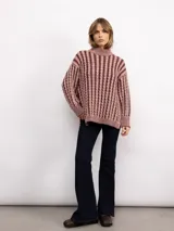 Sweater de punto con diseño de trenzas verticales, cuello alto y silueta oversize. Presenta un patrón bicolor en tonos azul y azul oscuro, con mangas largas y terminaciones en tejido acanalado.
