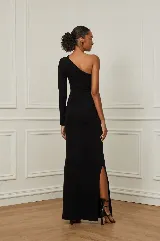 Vestido largo negro de un solo hombro, con manga larga y abertura lateral en la falda.
